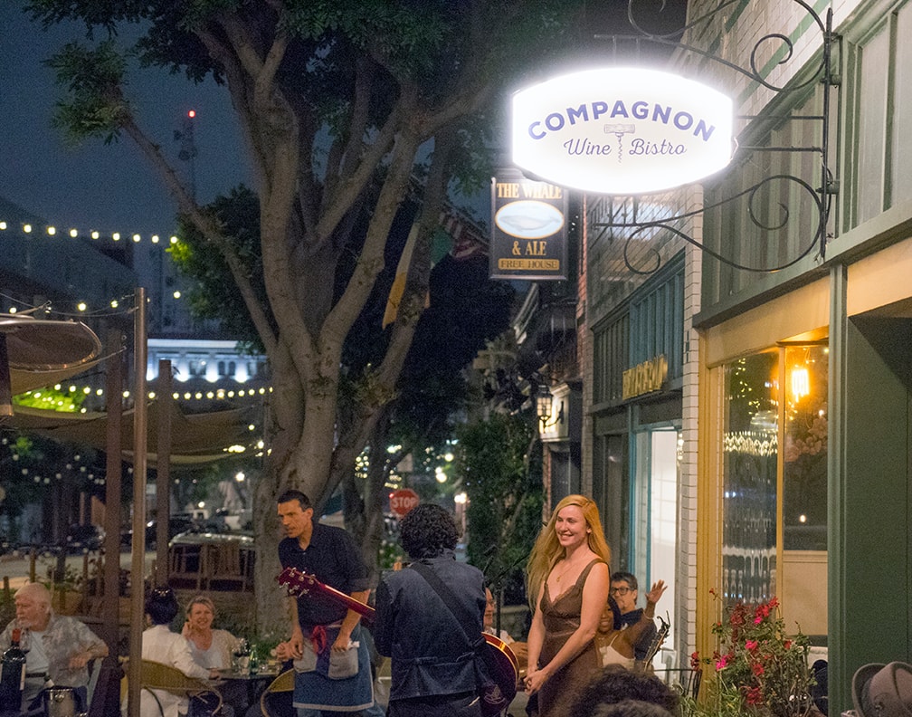 Compagnon Wine Bistro exterior at night with live music and guests.