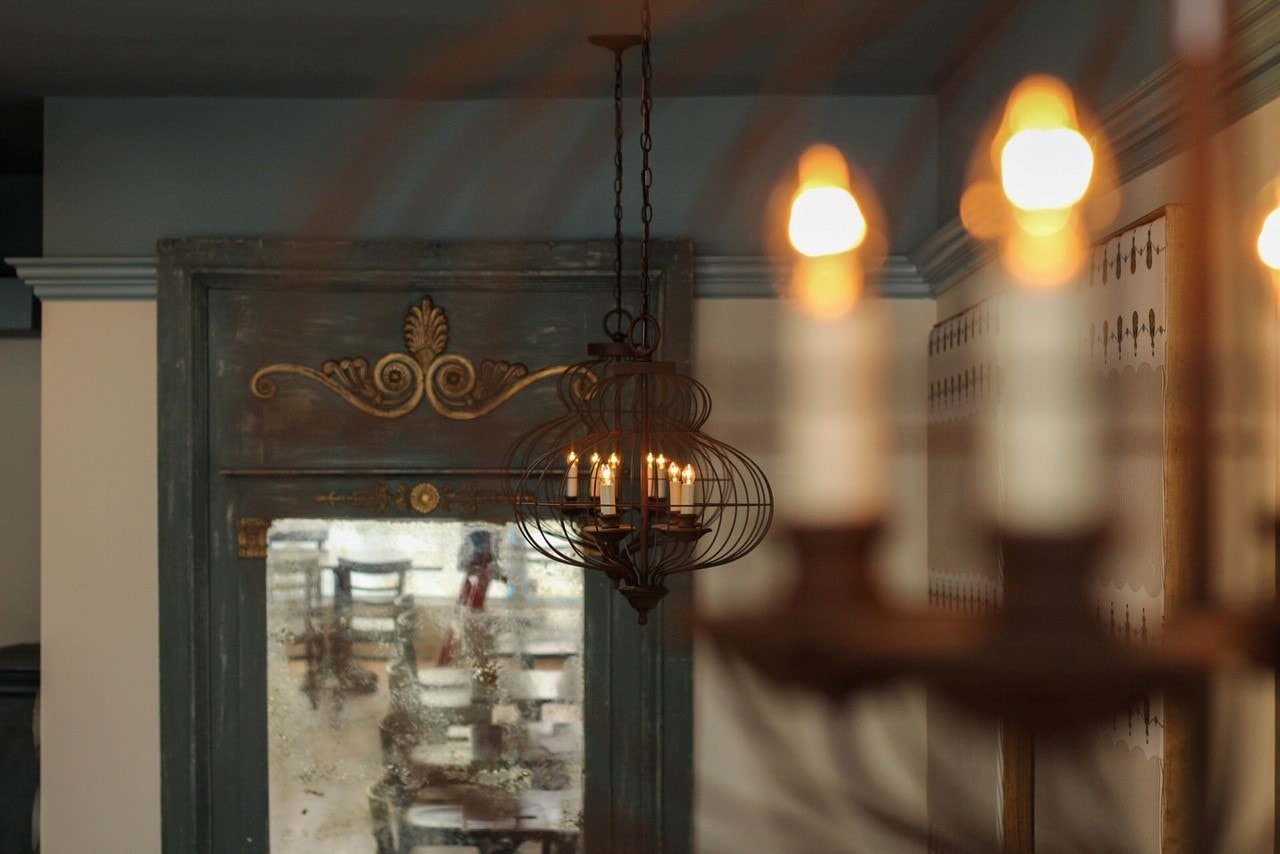 Warm interior with ornate mirror and birdcage chandelier.