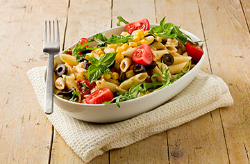 A bowl of pasta salad with tomatoes, corn and lettuce.